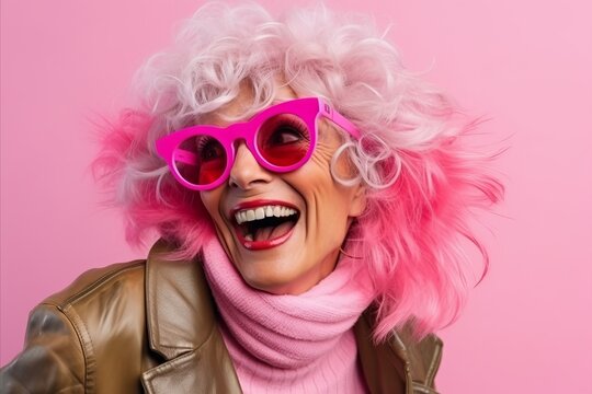 Fashionable woman with pink hair and sunglasses on a pink background