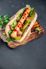 Hot Dog sausage bun, tomato sauce, pickled cucumber, green lettuce leaf takeaway food tasty fresh eating appetizer meal food snack on the table copy space