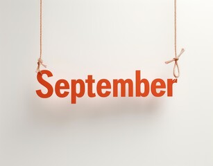 The word "September" written in bold red letters individually hanging from a rustic rope. Rope tied in knots suspended in the air on a clean white background.