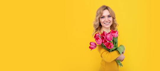 smiling young woman with spring tulip flowers on yellow background. Woman isolated face portrait,...