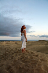 Young woman stands in the sand dunes
