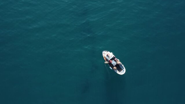 drone, vista dall'alto. Movimento ad allontanarsi, Pescatore su piccola barca in mare limpido e azzurro.