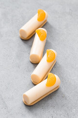 Tangerine cream dessert bars. On cookies. Decorated with a slice of tangerine. Light gray background. Close up