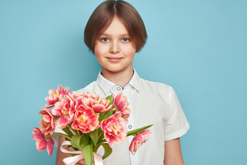 Cheerful happy child with Tulips bouquet. Smiling boy on blue background. Mother's Day. Love and romantic concept