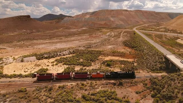 Aerial Tilt Down Shot Of Railway On Railroad Track In Semi Arid Desert Under Cloudy Sky During Sunny Day - Ely, Nevada