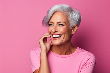 Portrait of beautiful smiling middle aged woman with grey hair on pink background