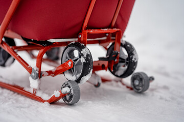 Beautiful red children's sled in the snowy pine forest of winter, enjoying sleigh ride