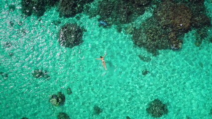 Top down woman snorkeling crystal turquoise sea water coral reef, aerial view, drone shot. Slim girl in bikini enjoy outdoor activity lifestyle, travel summer holiday vacation. Tahiti, Polynesia.