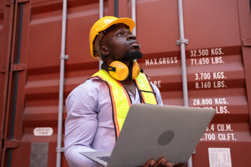 African American foreman holding notebook computer with container background