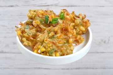 corn fritters in a skillet with yogurt dipping sauce and fresh sweet corn in cob on an old rustic kitchen table, view from above Vegetarian food, Thai food, snacks Thai style. Homemade Fried Cheddar 