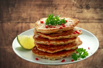 corn fritters in a skillet with yogurt dipping sauce and fresh sweet corn in cob on an old rustic...