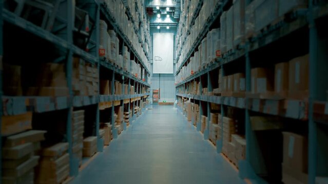Walking Through Warehouse Corridor Products Store Tracking Shot. Walking through a big warehouse corridor with shelves full of boxes, slow motion. Tracking shot