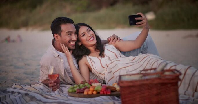 Happy couple, picnic and beach for selfie, date or memory together in photography, picture or outdoor bonding. Man and woman with smile in relax for photo or capture moment by fruit basket on blanket