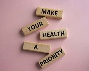 Health symbol. Wooden blocks with words Make your health a Priority. Beautiful pink background. Health concept. Copy space.