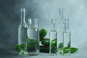 Glass water bottles and fresh green zucchini on a textured gray surface