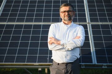 Solar power plant. Man standing near solar panels. Renewable energy