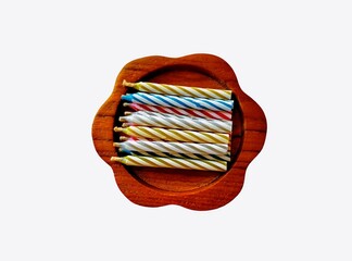 The white background in the picture has a small terracotta candle pot with an orange candle and a white light string, and a tray of blue candles placed nearby.