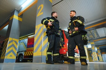 Group of firefighters at the emergency vehicle in the fire station