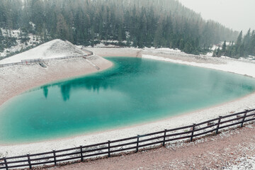 Heart shaped turquoise water alpine lake in Dolomites mountains, Cortina dAmpezzo, Italy in snowy spring day. Winter in spring with snow in Italian Alps