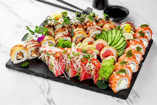 Assorted sushi platter with elegant garnishes on slate board