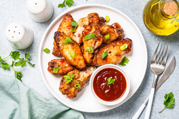 Grilled Chicken wings with sauce in craft plate at white table. Top view.