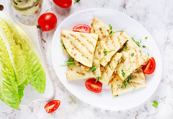 Mexican Quesadilla wrap with chicken, corn and sweet pepper on white plate. Top view