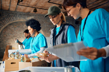 Group of volunteers sorting food in donation boxes at humanitarian aid center.