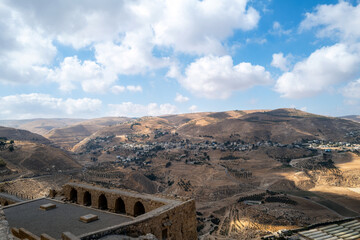 Valley canyon view sandstone architecture, no people. dry desert heat. Residential buildings, blue sky clouds. Middle Eastern town or village. Arabic lifestyle. deep contrast shadow from cloudy sky