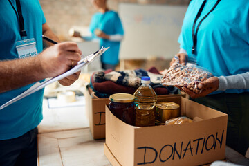 Close up of charity workers sorting donations into boxes at humanitarian aid center. - obrazy, fototapety, plakaty