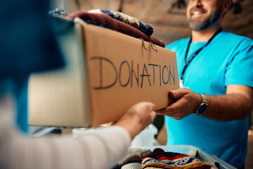 Close up of volunteers sorting donation boxes with clothes at community center.