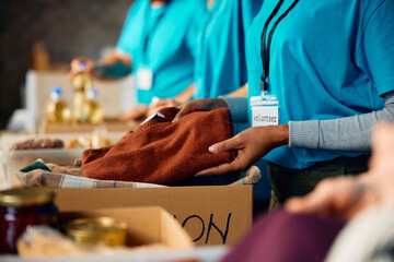 Close up of volunteer packing donated clothes into cardboard boxes at community center.