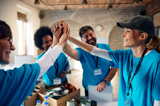 United team of volunteers gathering their hands while working at community center.
