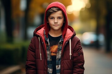 Portrait of a boy in a red down jacket on the street.