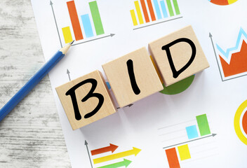 work desk with financial charts. text on wooden blocks BID
