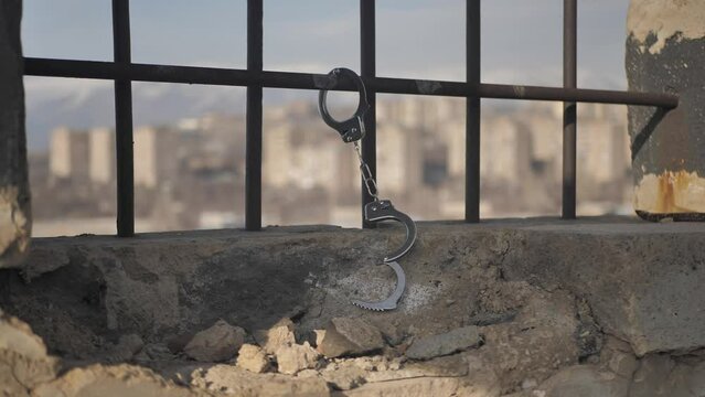 Inside the prison cage, handcuffs hang unfastened on the metal bars of the window. Release from prison concept. end of the prison term. Posting bail and releasing. Exchange of prisoners of war
