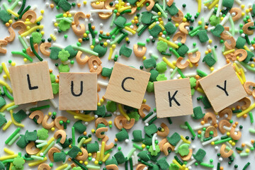 The word Lucky spelled out in wooden tiles on a collection of St. Patrick's Day themed sprinkles,...