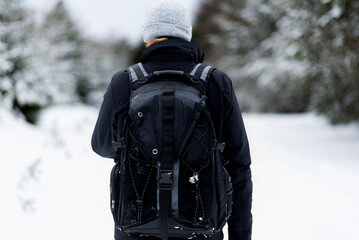 Back view of hiker in winterly forest with blurred background