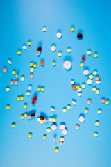 Colorful pills and capsules on blue background. Minimal medical concept. Flat lay, top view.