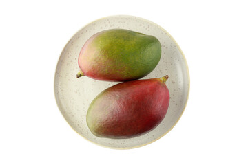 Two whole ripe mango Palmer fruits on retro plate isolated on white