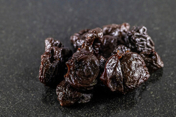A close up view of dried prunes in a pile on a dark marble platter