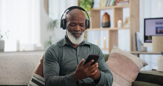 Phone, music and senior black man on sofa in living room of retirement home to relax with headphones. Radio, streaming and weekend with elderly person listening to audio on mobile app in apartment