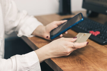 Woman's hands holding credit card and using mobile phone and pc on a table for online shopping,...