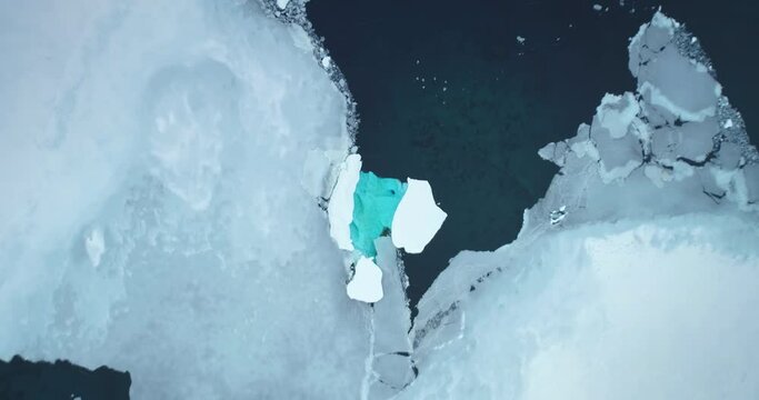 Crashed ice glacier in Antarctica aerial top view. Huge iceberg with melting blue water hole inside, polar nature environment. Arctic winter landscape at global warming problem. Zoom in drone shot
