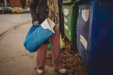 one woman stand with paper garbage in front of recycle containers