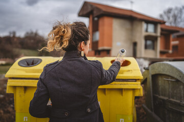 one woman stand with plastic garbage in front of recycle containers