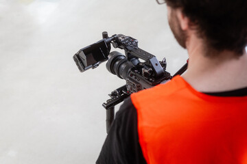 Professionelle Video-Kamera auf Stativ wird von Mann mit Sicherheitsweste bedient