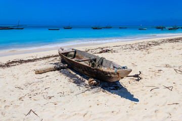 Old wooden boat ashore on tropical sandy Nungwi beach in the Indian ocean on Zanzibar, Tanzania
