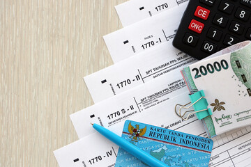 Annual Individual Income Tax Return forms with pen and indonesian rupiah bills. Original name is Surat Pemberitahuan Pajak or SPT Tahunan