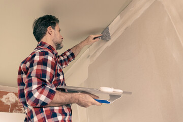 Home renovation - handyman (contractor) plasters gypsum boards walls (plasterboards, drywalls)....