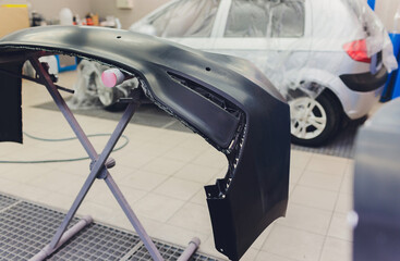 Auto mechanic preparing the car for paint job by applying polish with the power buffer machine